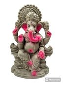 A clay Ganesh idol with pink highlights, sitting in a meditation pose, against a white background.