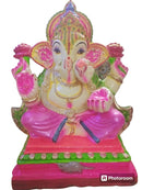 A colorful clay statue of Lord Ganesha, with vibrant pink and green details, seated on a pink base with ornate gold and silver decorations.
