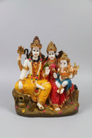 A colorful statue of Hindu deities, including Shiva, Parvati, and Ganesha, seated together .