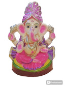A colorful statue of Lord Ganesha, the Hindu god of wisdom, sitting on a platform with a pink and gold design, surrounded by floral patterns.