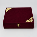 A rectangular dark burgundy velvet jewelry box with ornate gold corner 