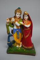 Lord Krishna and Radha standing together on a green base, with a peacock at their side. 