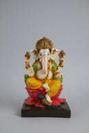 A colorful Ganesha statue seated on a pink lotus base,